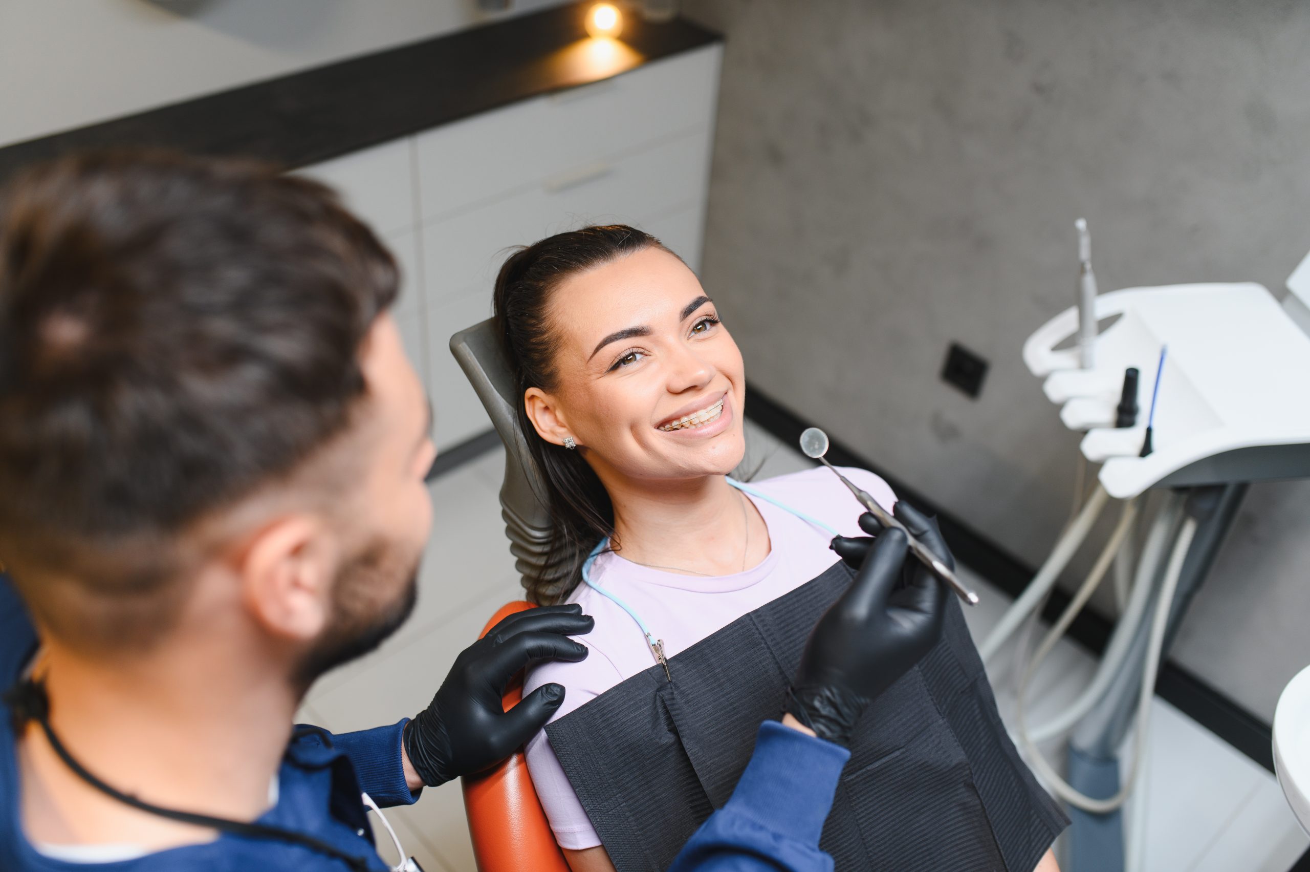 a female dentist wearing a medical mask and rubber gloves poses for the camera and folds her arms in her office