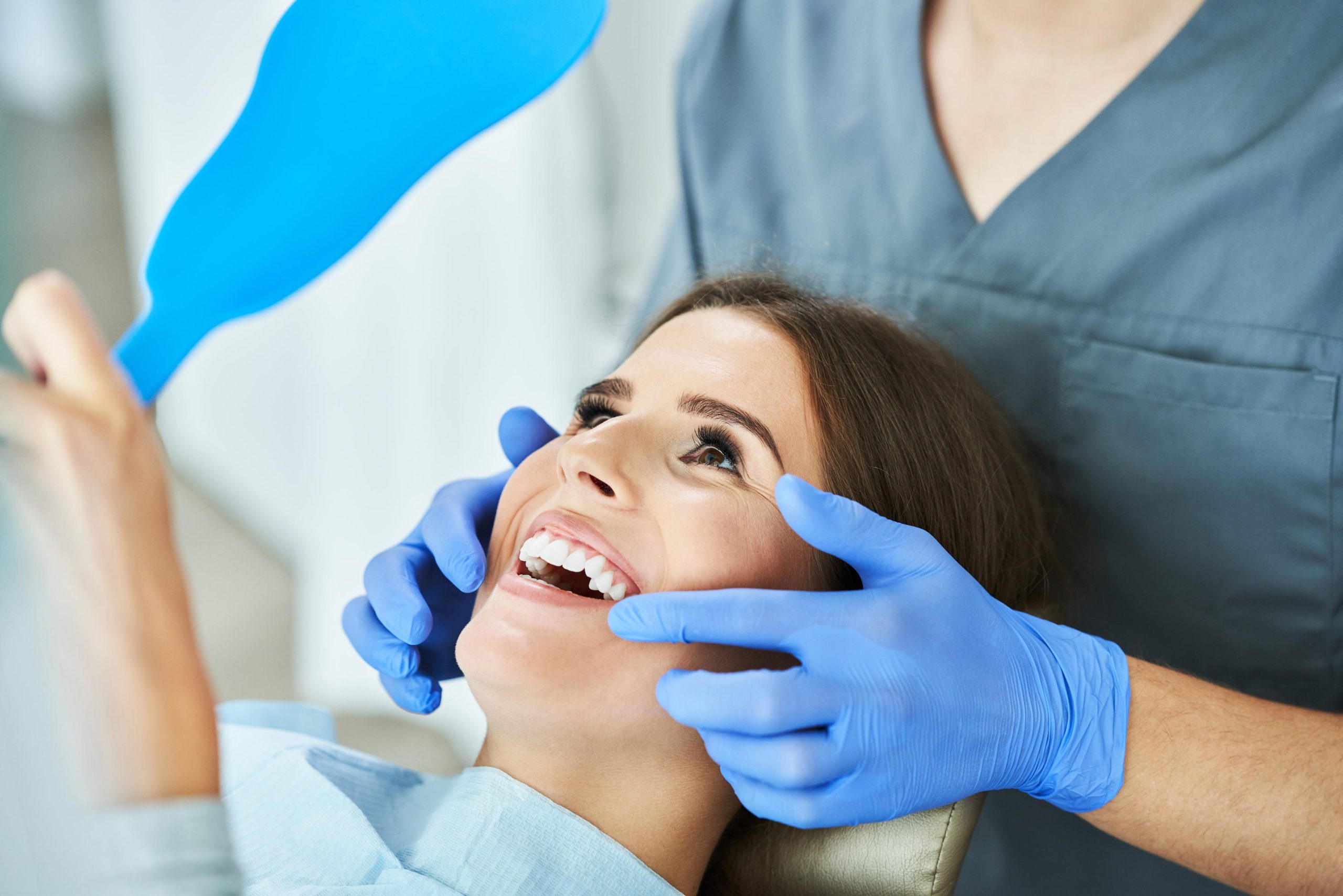 a female dentist wearing a medical mask and rubber gloves poses for the camera and folds her arms in her office