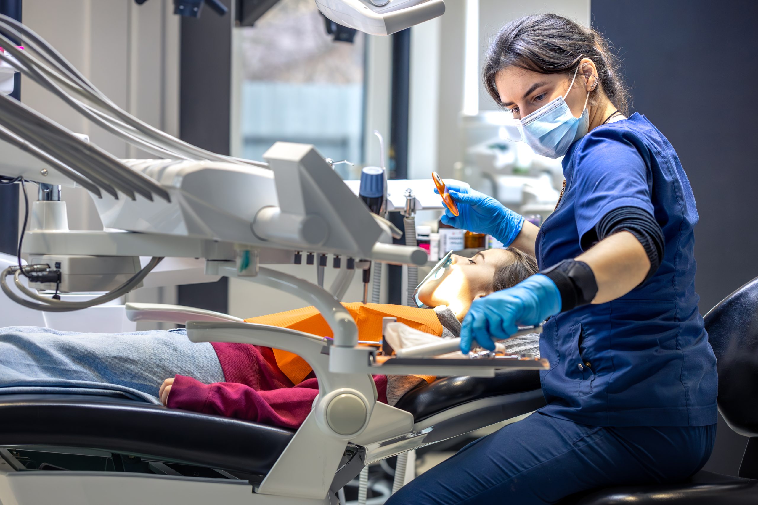 Young female dentist in dental office. Dentist at work. Dental treatment concept.